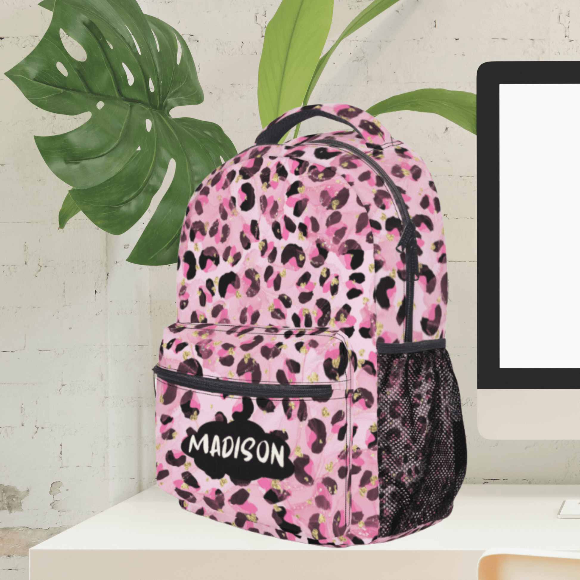 The back to school carry on bag for kids has the name on the front pocket and is shown sitting on a desk.