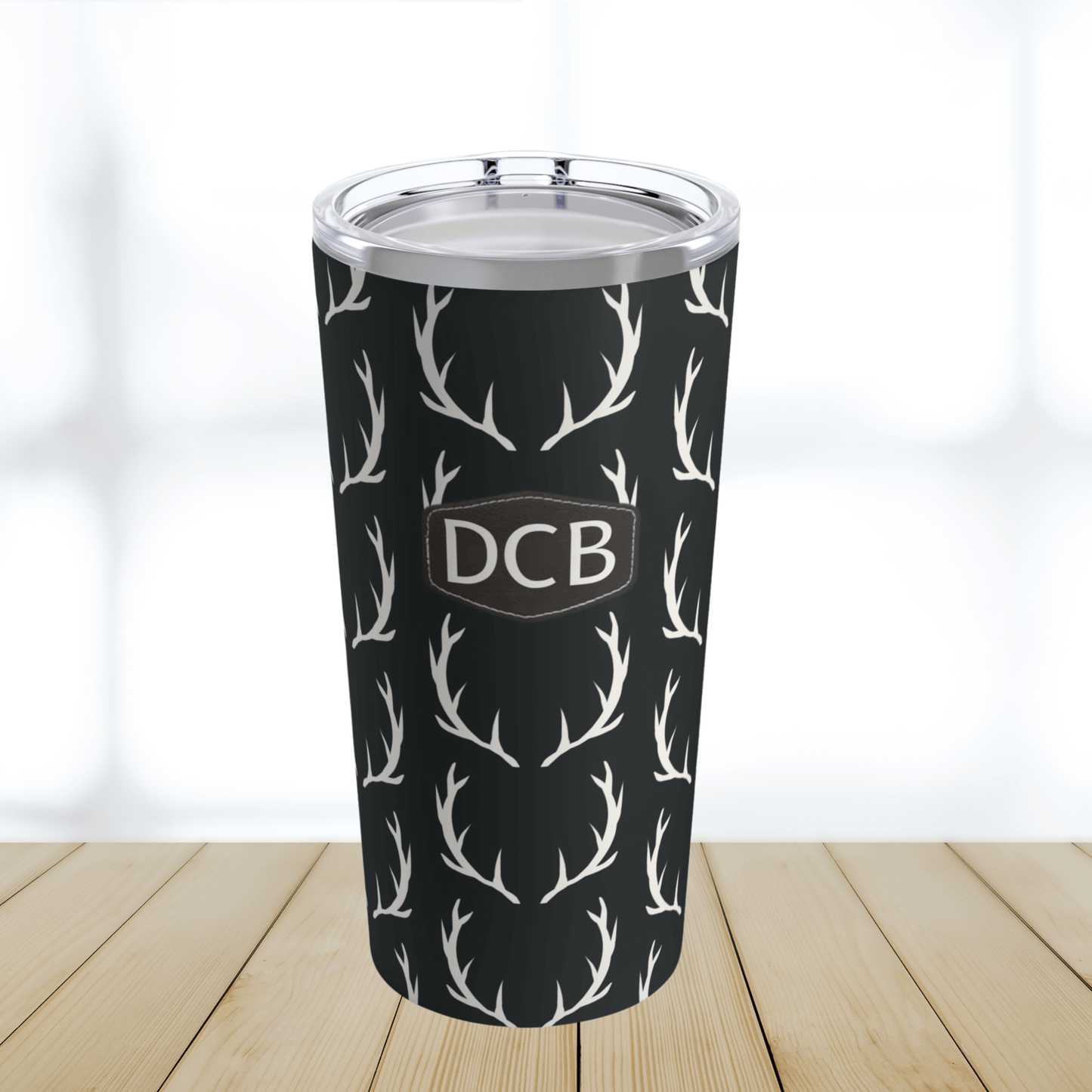 Our monogrammed deer antler tumbler cup for men is a twenty ounce black tumbler with off white deer antlers all over the cup and a brown leather print patch with three monogrammed initials on the front. This cup makes a perfect gift for men & hunters
