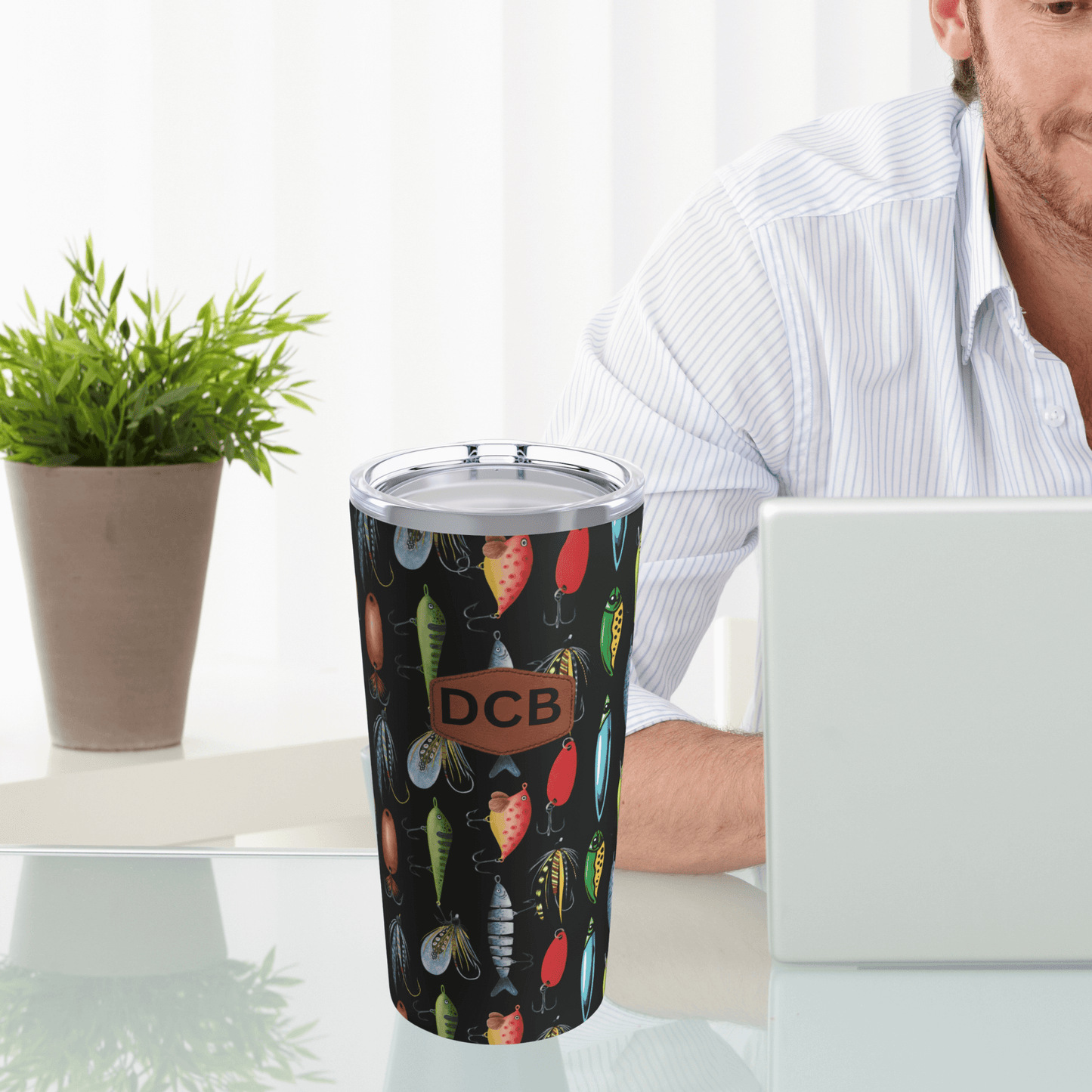 Our fishing travel mug is shown next to a man working on a computer
