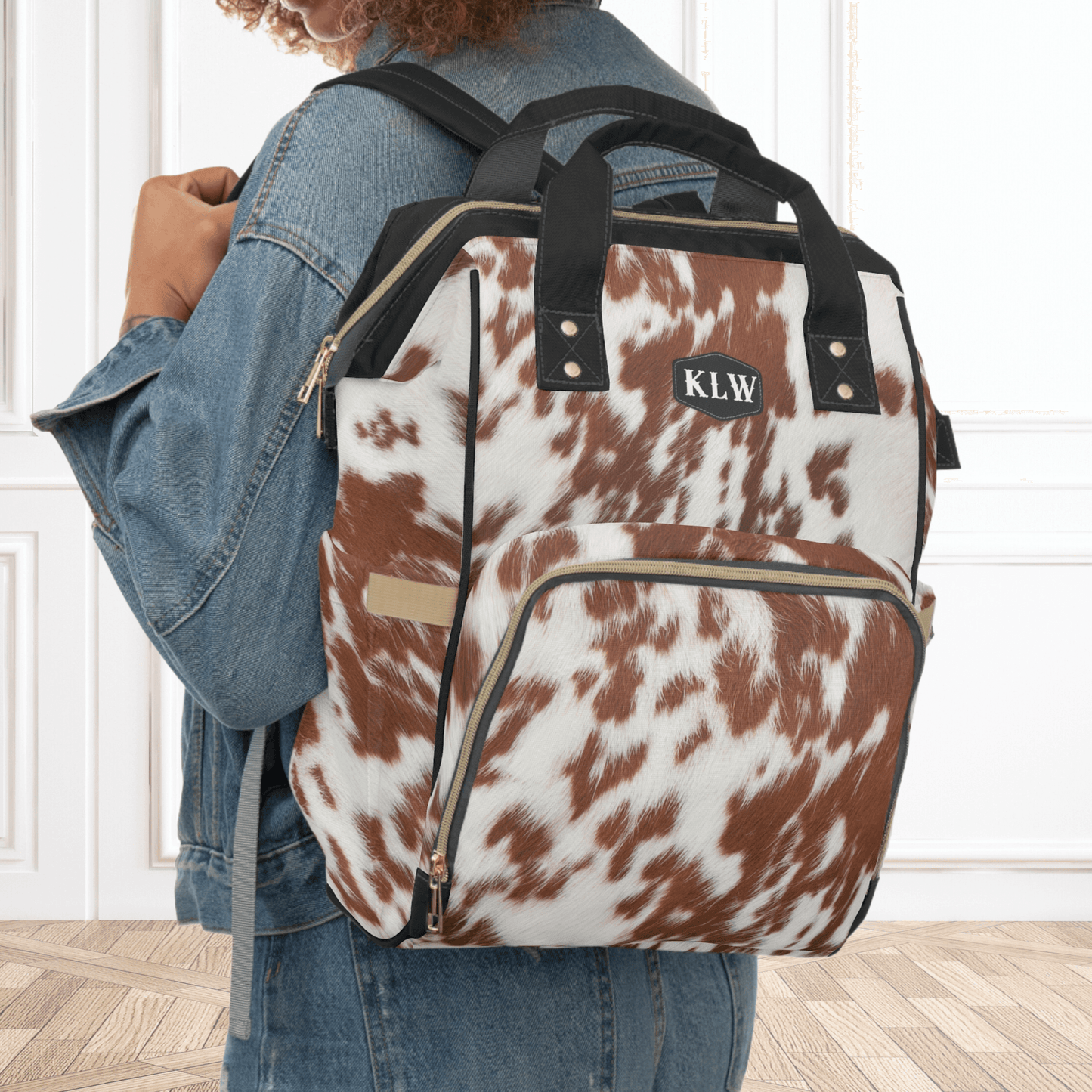 Our cowhide print baby bag can double as the perfect Western style carry on for airplanes and is shown with the model wearing it as a backpack. 