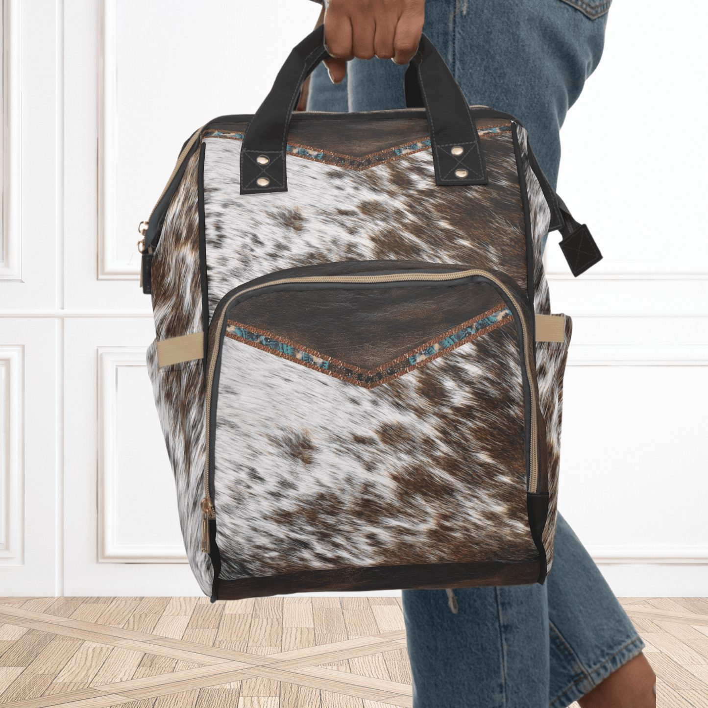 Our cowhide print multipurpose backpack can be held by the top black handles, as shown here. This cowhide print with leather print is a showstopper and can be monogrammed or enjoyed plain as in this picture. 