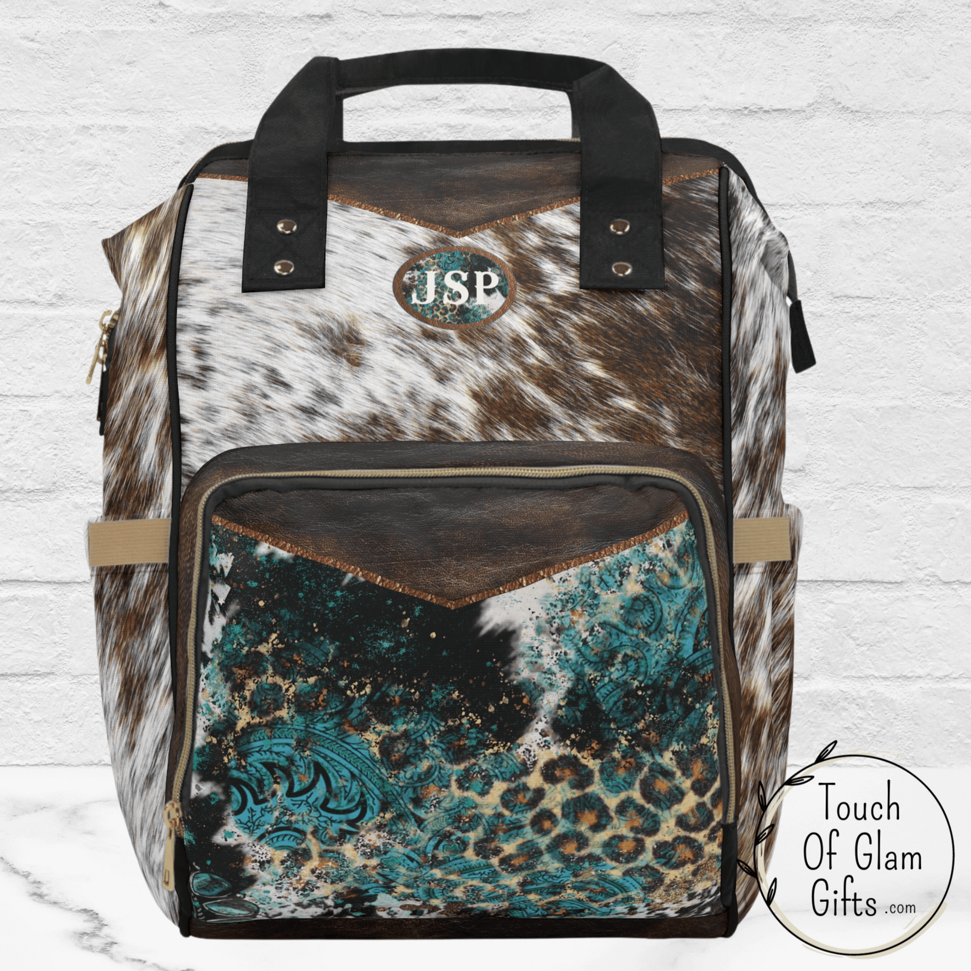 Our custom made diaper bag backpack with brown cowhide print shows the monogrammed initials on the front with a turquoise patch. This diaper bag makes the perfect, unique baby shower gift for new parents that want a bag that lasts.