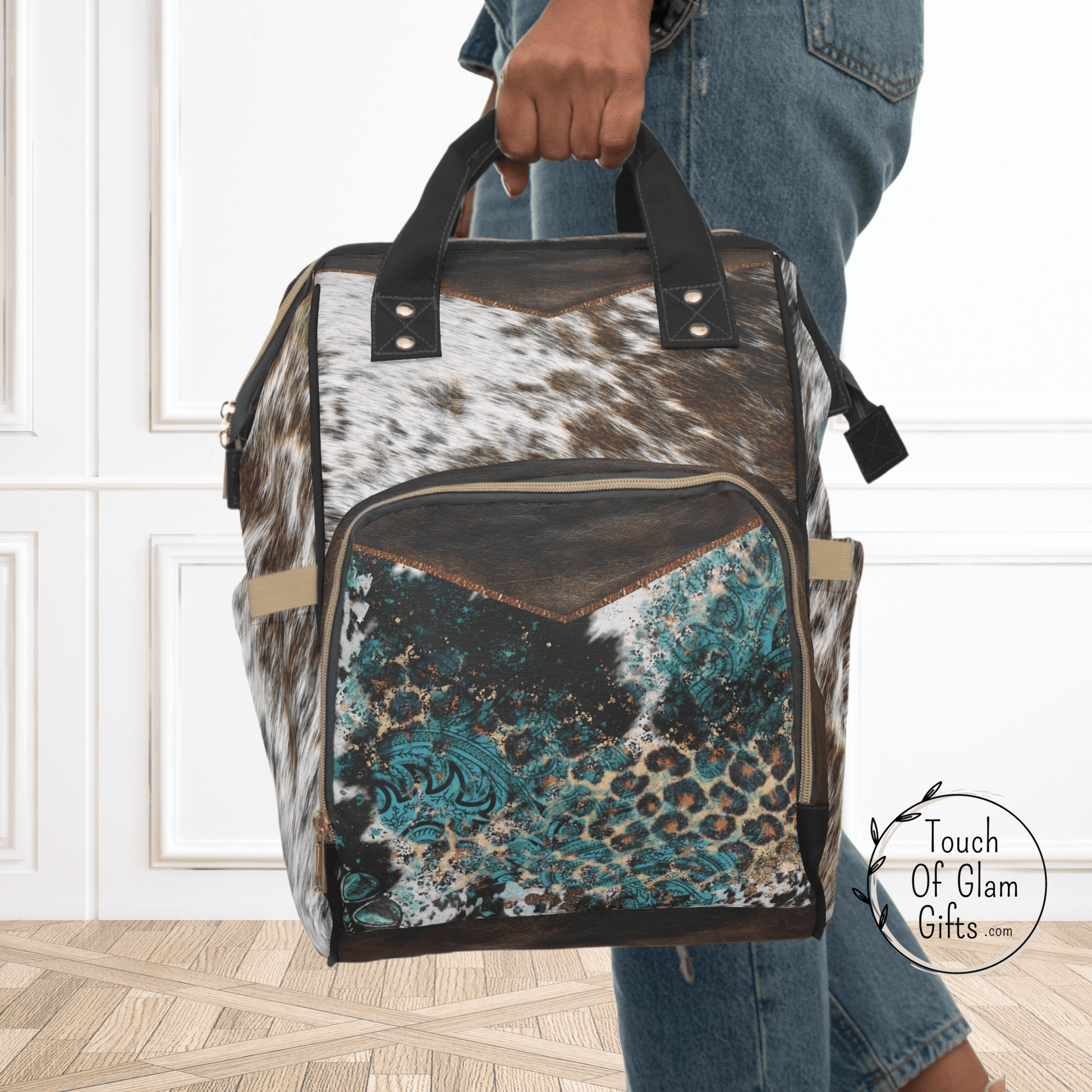 Our western diaper bag backpack makes the perfect baby shower gift for new moms. This timeless cowhide print on durable nylon fabric makes it cleanable too. the front pocket has a touch of turquoise and more animal prints for a trendy travel bag.