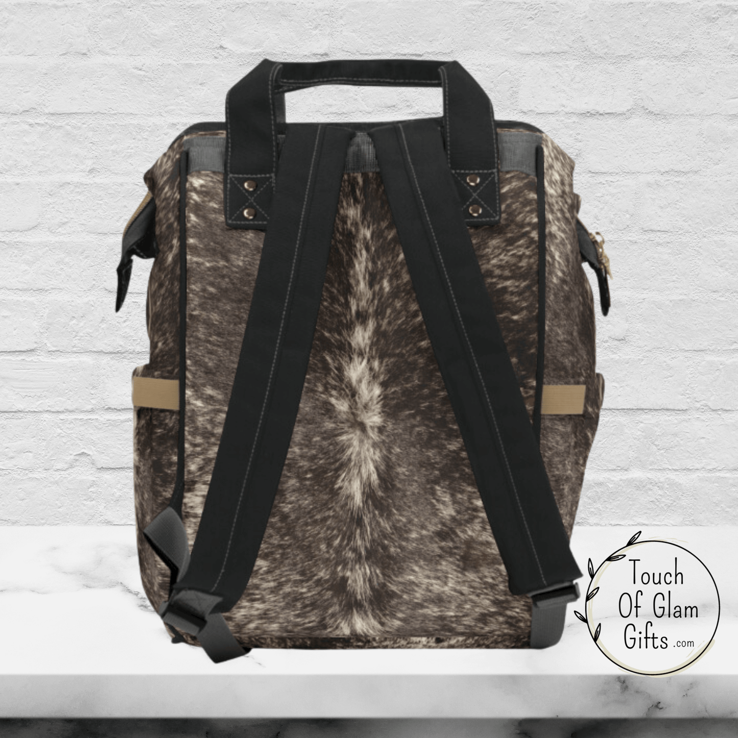 The back side of our cow print backpack shows the padded shoulder straps in black and handles in black.