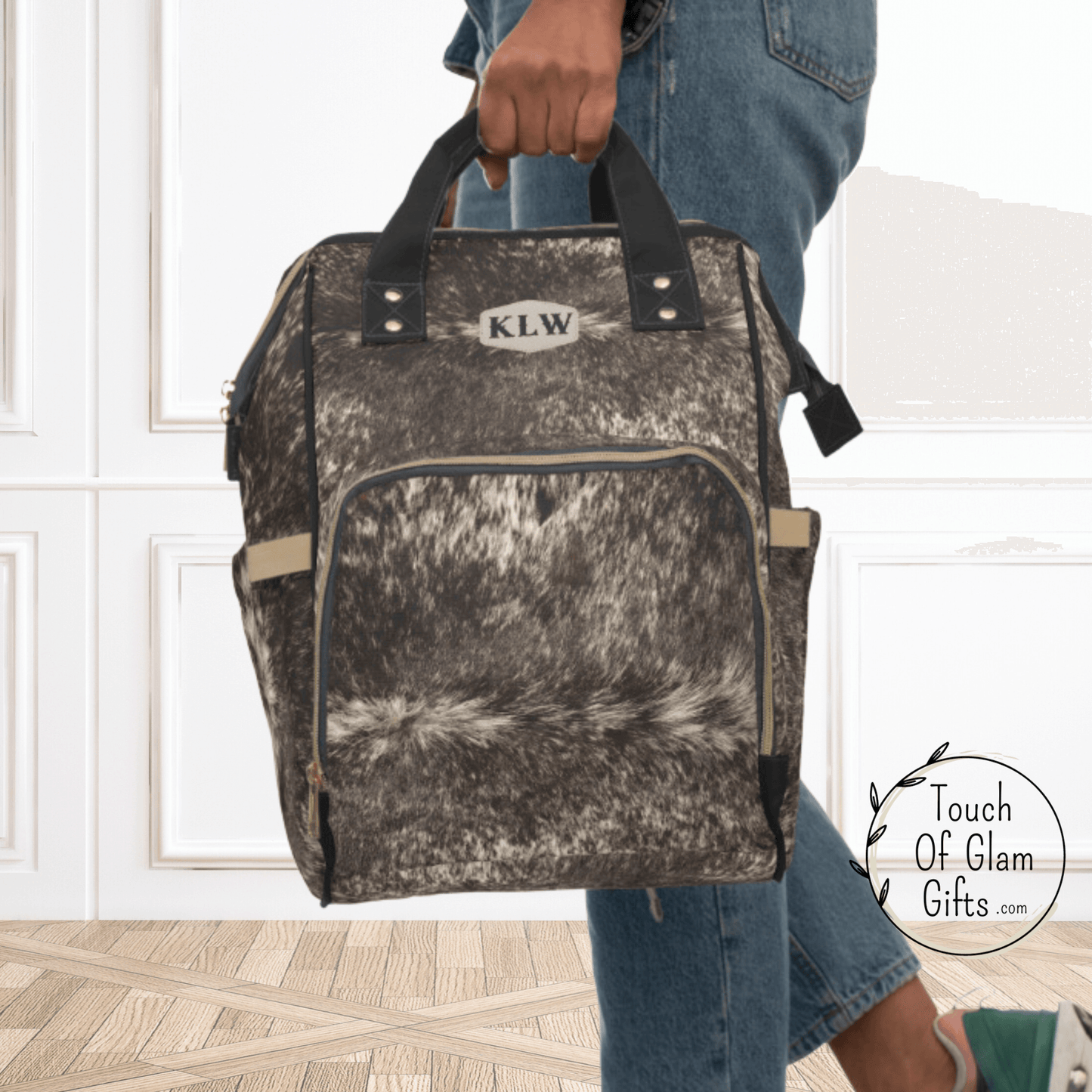our diaper bag backpack in cow print brown can be carried with the comfortable handles.