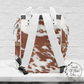 The back of our backpack is rust colored cowhide with shades of white and white straps.
