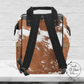 The backside of our cow print backpack shows the black padded shoulder straps and black handles.
