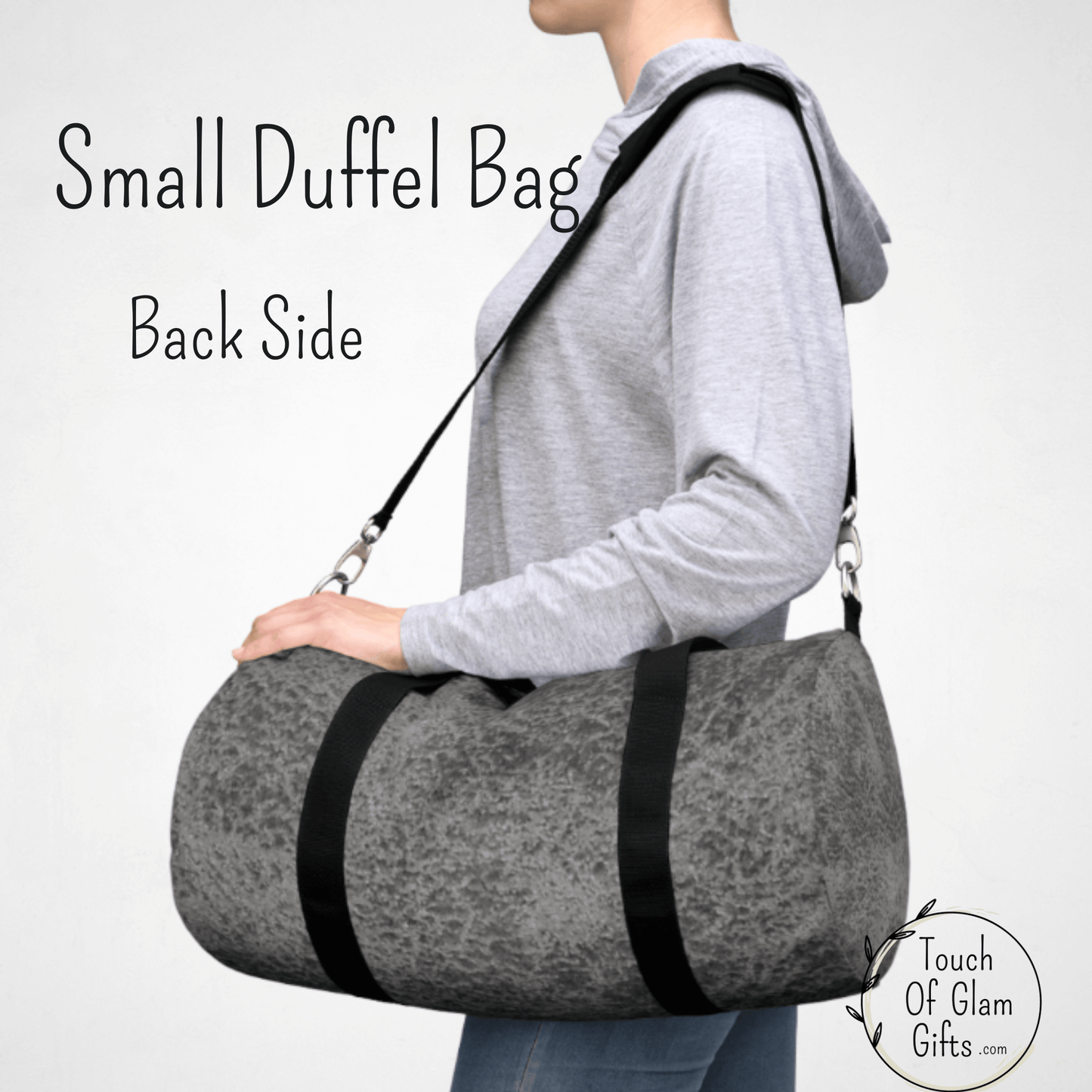 A female model has the small carry on duffel bag over her shoulder to show the size of the weekend bag in grey.