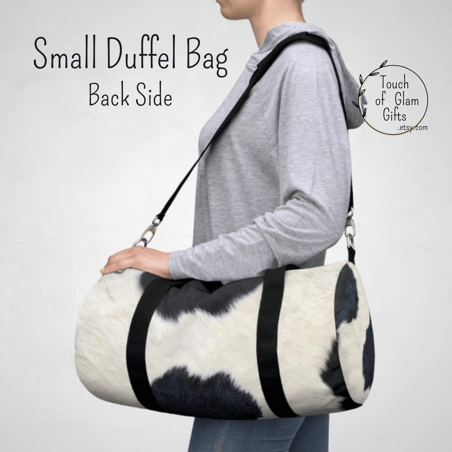 Our female model  has the small cow print duffel bag over her shoulder with the black straps and it shows the size of the smaller duffel bag.