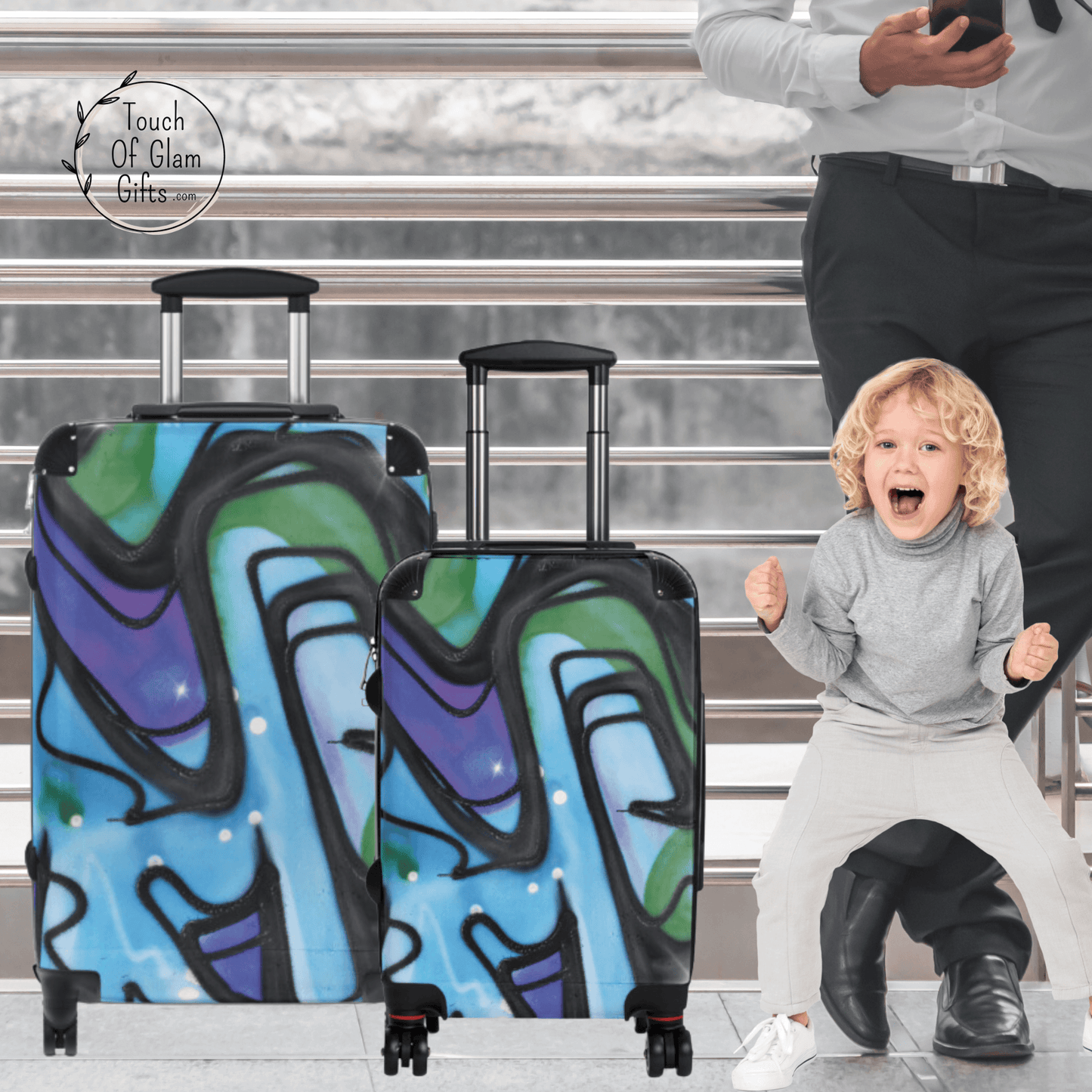 A boy is excited about his cool blue luggage with a graffiti design.  He has the medium size suitcase with wheels and small carry on suitcase.