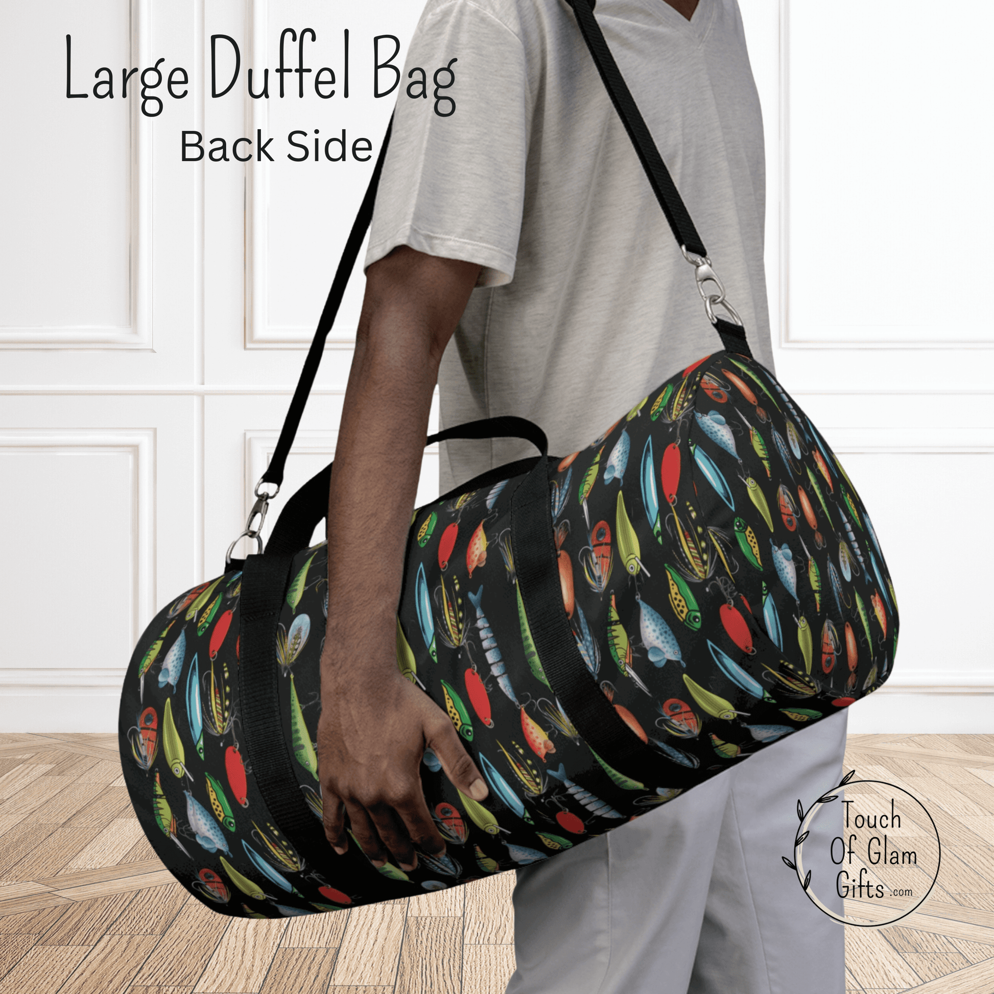 Our large duffel bag for outdoorsmen makes a great personalized fish gift for dads, men and sons. This shows the shoulder bag on a male model with the back side of the bag shown and black straps and fishing lure design on black material.